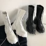 Paire de bottes blanches et noires à lacets sur un fond blanch et un sol noir et blanc