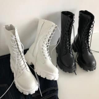 Paire de bottes blanches et noires à lacets sur un fond blanch et un sol noir et blanc