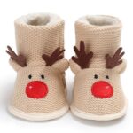 Très jolies bottes en mailles tricotées esprit de Noël, beiges, avec un motif renne de Noël : deux petites cornes dépassent sur le dessus de la botte fourrée et des yeux et un nez rouge sont cousus en-dessous.