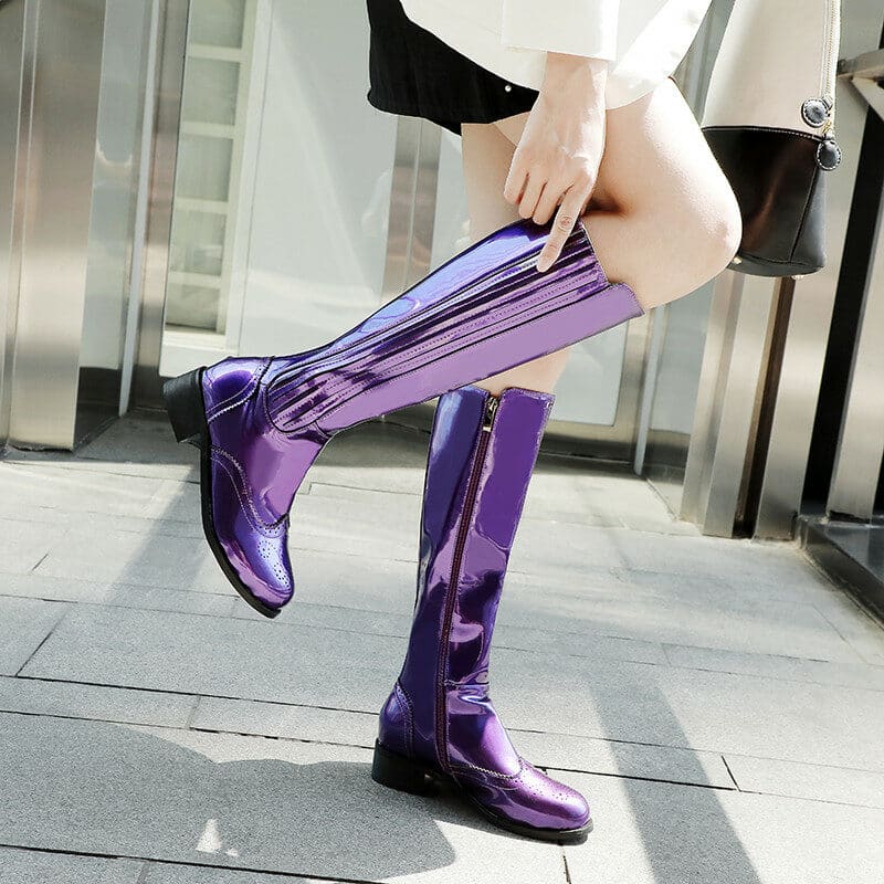 Jambes de femme portant des bottes violettes sur un pied, dans la rue.