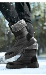 Paire de bottes de neige fourrés noires, un pied est levé par rapport à lautre