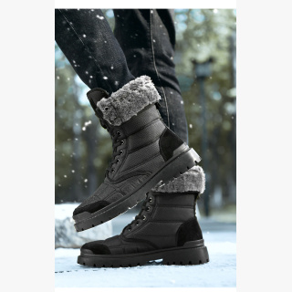Paire de bottes de neige fourrés noires, un pied est levé par rapport à lautre