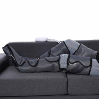 bottes grises massantes de pressothérapie avec télécommande sur un canapé gris