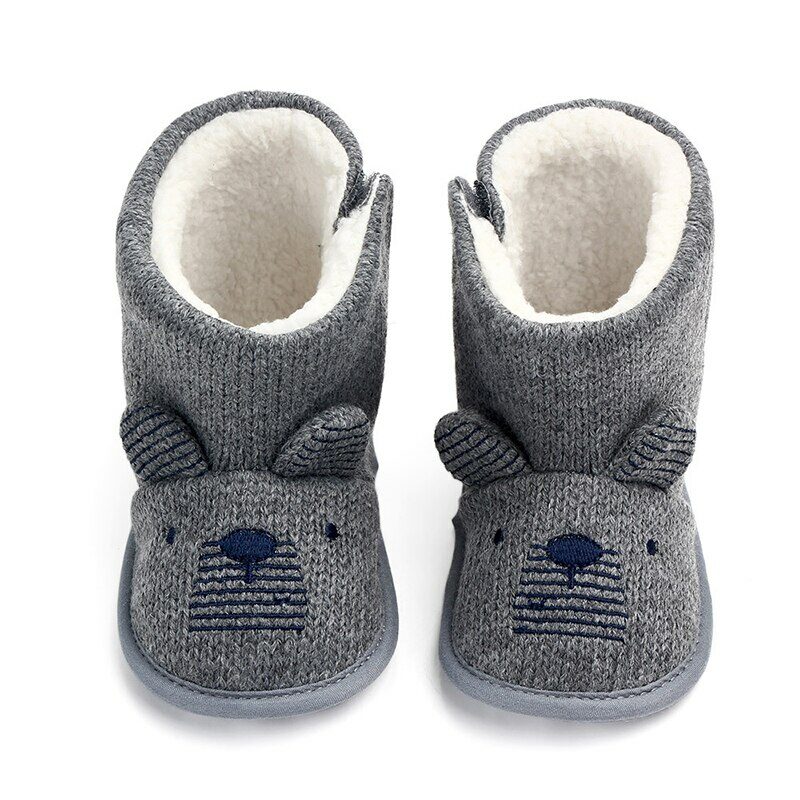 On voit une paire de bottes grises très mignonnes pour bébé. Sur le devant, il y a deux petites oreilles d'ourson qui dépassent. Les bottes sont fourrées.