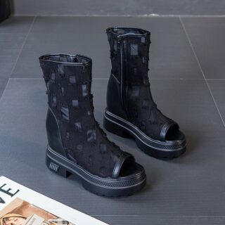 posée au sol, une paire de bottes noir d'été en dentelle avec des motifs carrés , elle se trouvent près d'un magazine et sur un carrelage gris