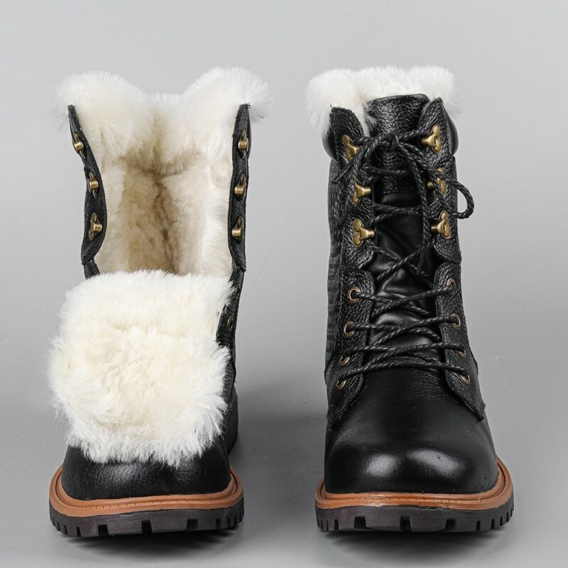 Paire de bottes d'hiver à lacets, noire avec intérieure en fourrure blanche. La chaussure de gauche est ouverte de la languette et la chaussure de droite est lacet jusqu'en haut. Elles sont de face, côte à côte et sur un fond gris.